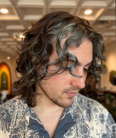 Client with shoulder-length dark curly hair and blue-green tinted face-framing curls